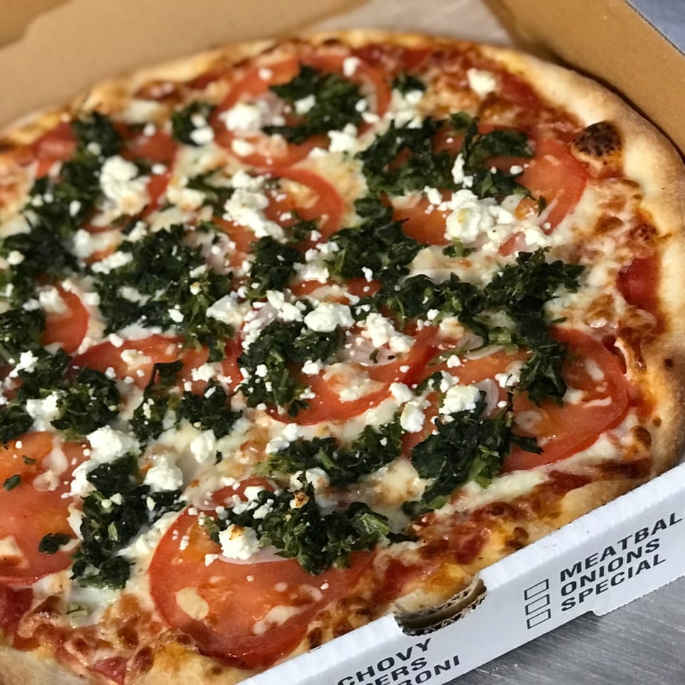 Sam's NY Pizza with tomatoes, spinach, and feta cheese in a pizza box.